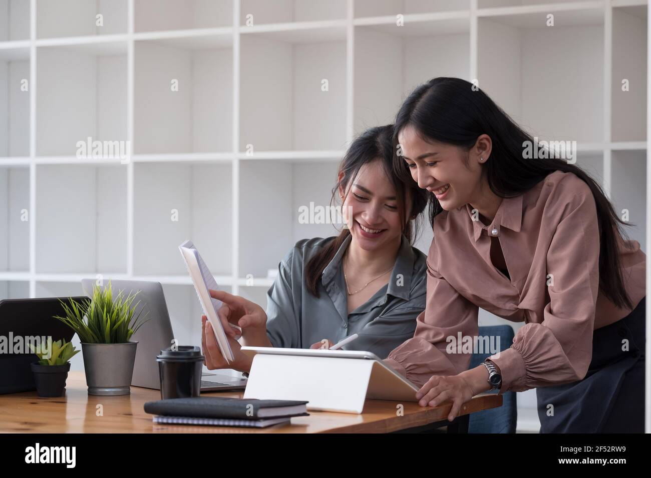Felici due donne che discutono i progetti di affari in un caffè mentre hanno il caffè. Concetto di startup, idee e tempesta di cervello. Foto Stock