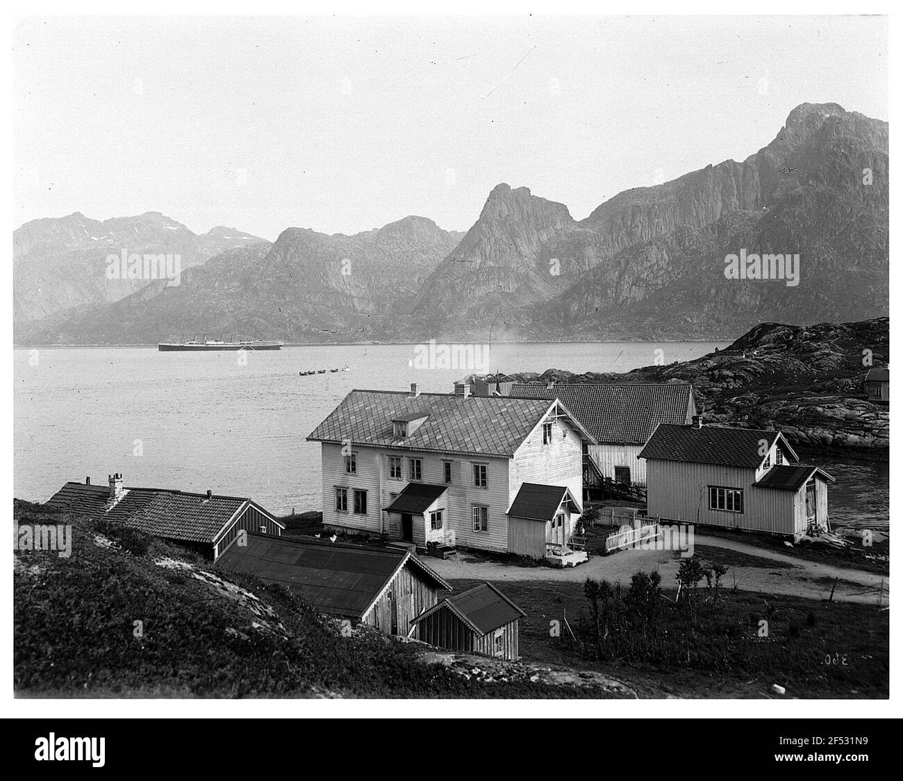 Digners su Hinnoy / Lofoten. Vista sulla proprietà sulla riva della baia con il vaporetto "Victoria Luise" per passeggeri in alto mare contro le montagne Foto Stock