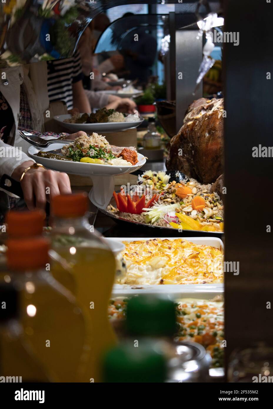 Mani che arrivano per il cibo in Arabic buffet con buffet di cibo orientale, sideboard che serve pasti in cui il cibo è collocato in un'area pubblica dove il din Foto Stock