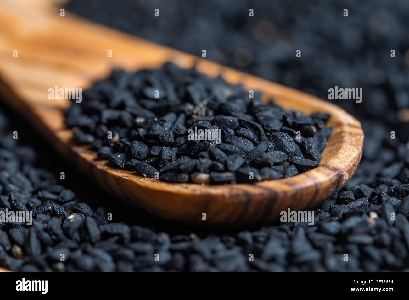 Semi di Nigella sativa, primi piani fotografici, con cucchiaio di legno, fuoco selettivo. Foto Stock