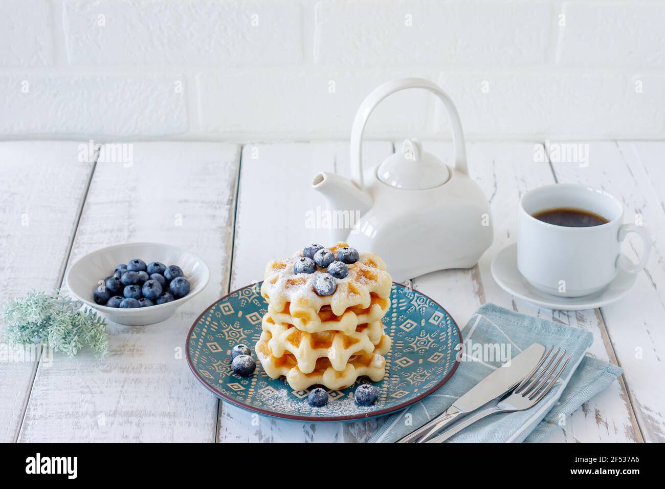 Colazione sana. Cialde belghe con mirtilli, zucchero in polvere e tè in legno Foto Stock