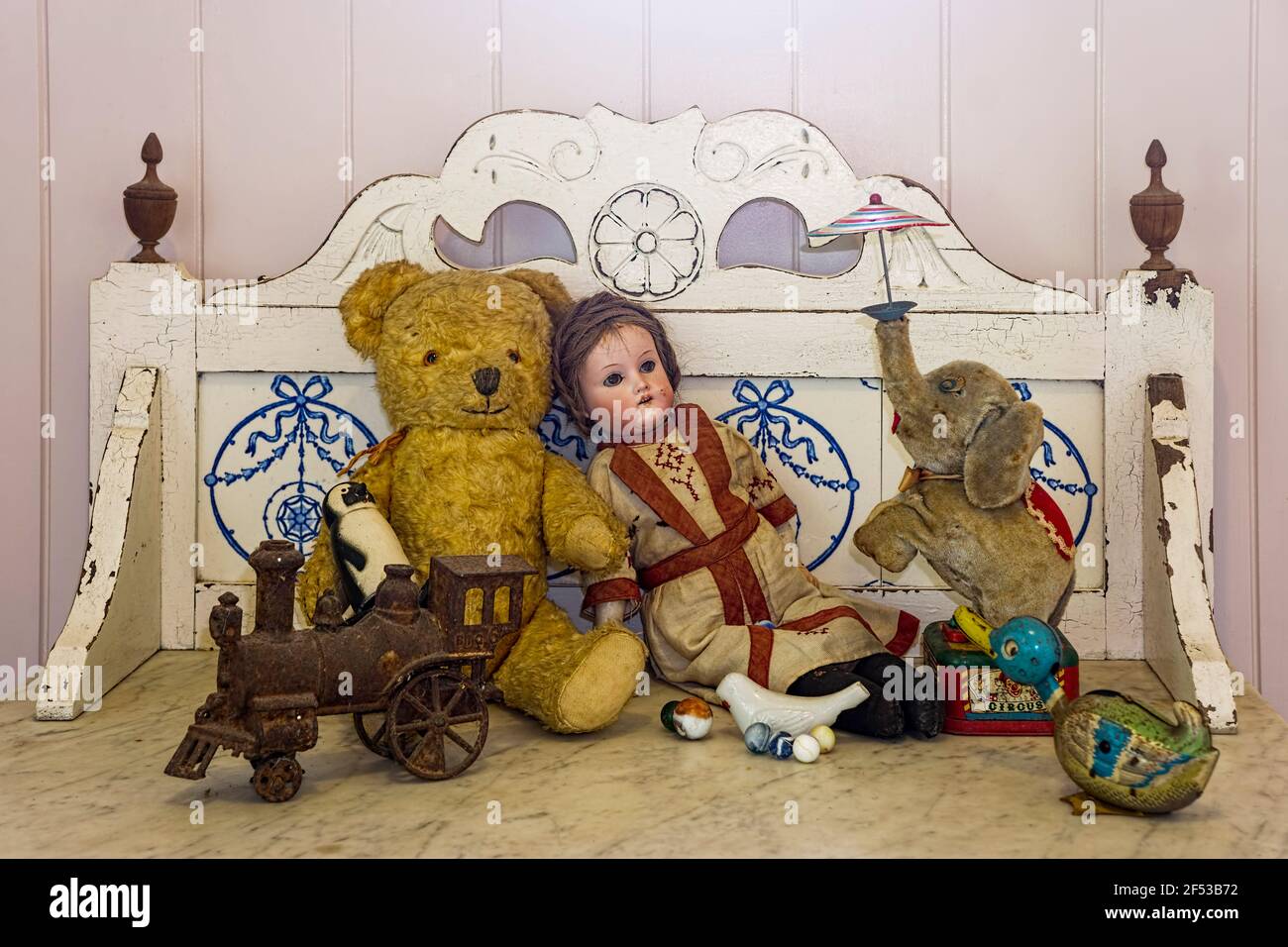 Vecchi giocattoli vintage e retrò, tra cui bambola, orsacchiotto, treno ed elefante su un antico lavabo in marmo. Foto Stock
