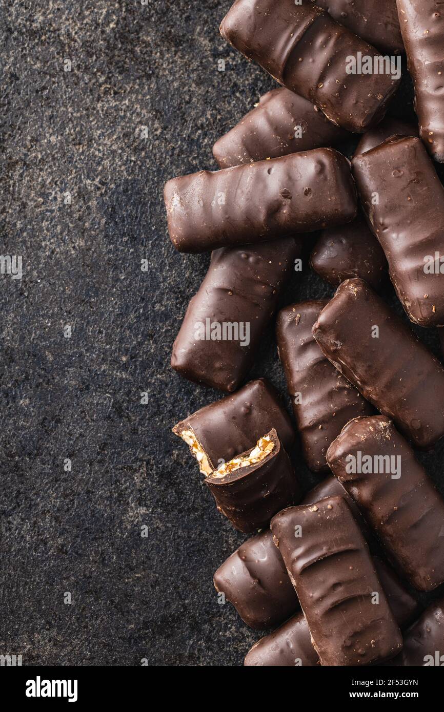 Barrette di cioccolato con noci ripieno su tavola nera. Vista dall'alto. Foto Stock
