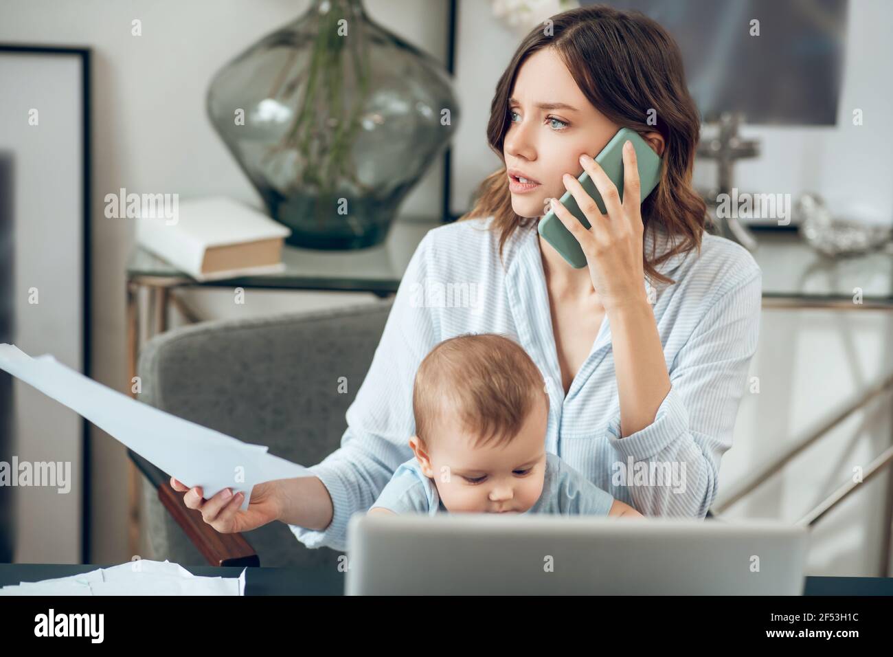 Donna con smartphone e documenti seduti con bambino Foto Stock