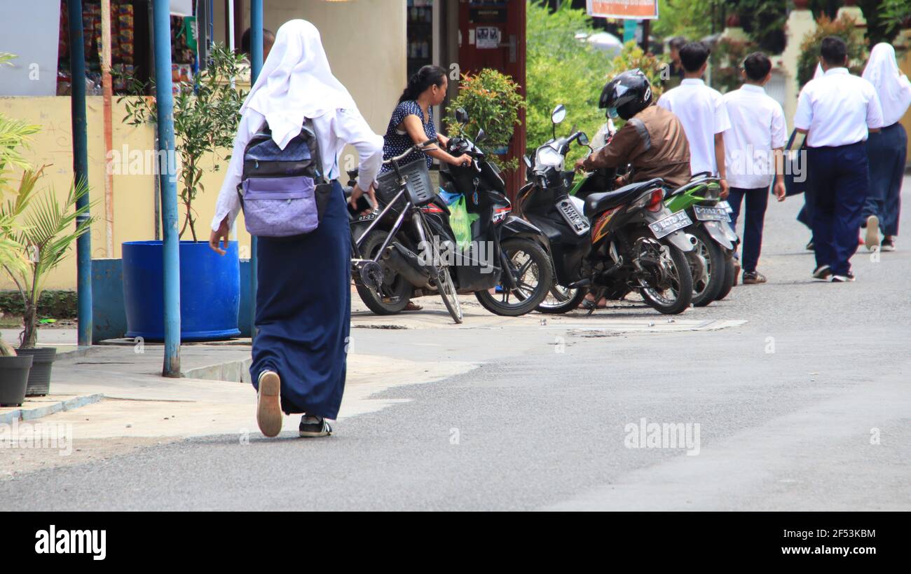 Bambini delle scuole superiori che camminano dopo aver studiato a scuola, indossando una maschera, Pekalongan, Indonesia, marzo 18, 2021 Foto Stock