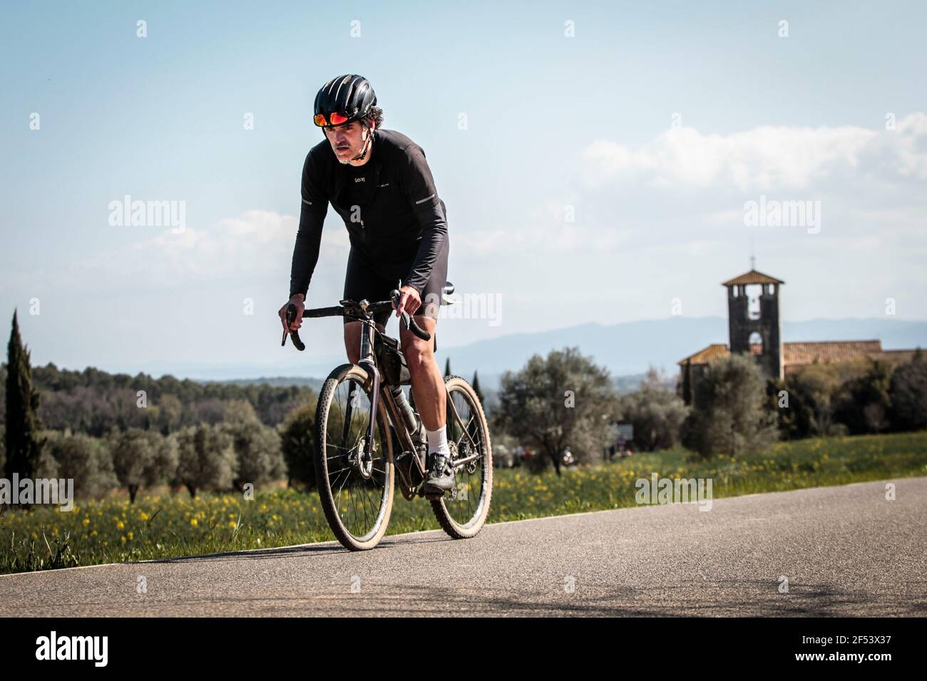 Uomo in bicicletta su una ghiaia attraverso Fontcoberta vicino Banyoles, Spagna Foto Stock