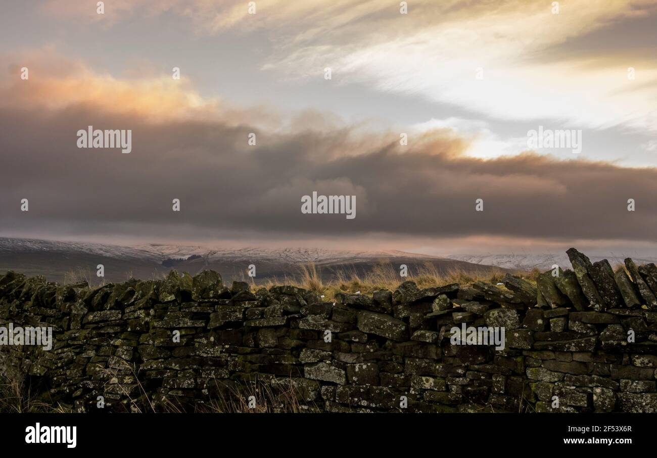 Un muro di pietra a secco con colline innevate oltre a Weardale, North Pennines, County Durham, Regno Unito Foto Stock