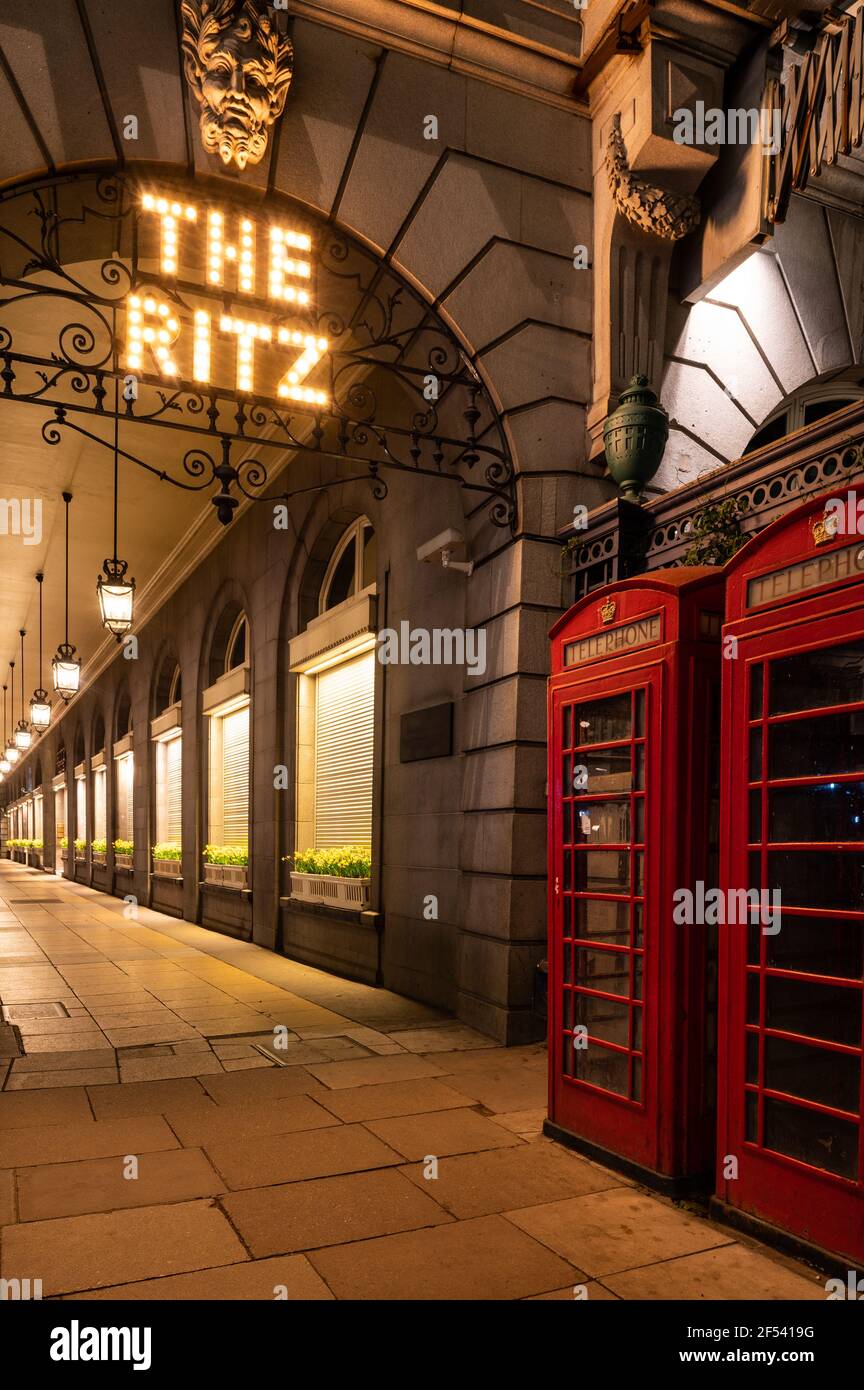Esterno del Ritz Hotel di notte e mostra ristorante l'arco e due tradizionali box telefonici rossi Foto Stock