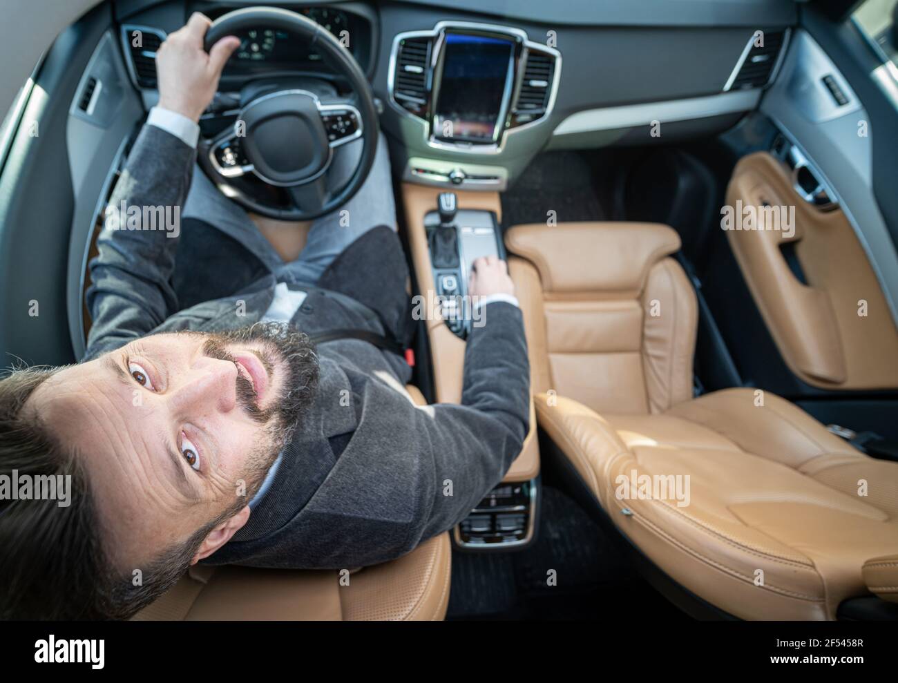 Divertente grandangolo di un driver maschile in auto di lusso Foto Stock