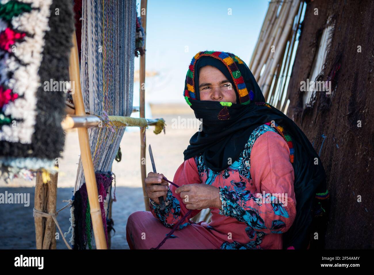 ERG Chebbi, Marocco - 12 aprile 2016: Una donna berbera tesse usando un telaio tradizionale in un villaggio vicino all'Erg Chebbi, in Marocco. Foto Stock