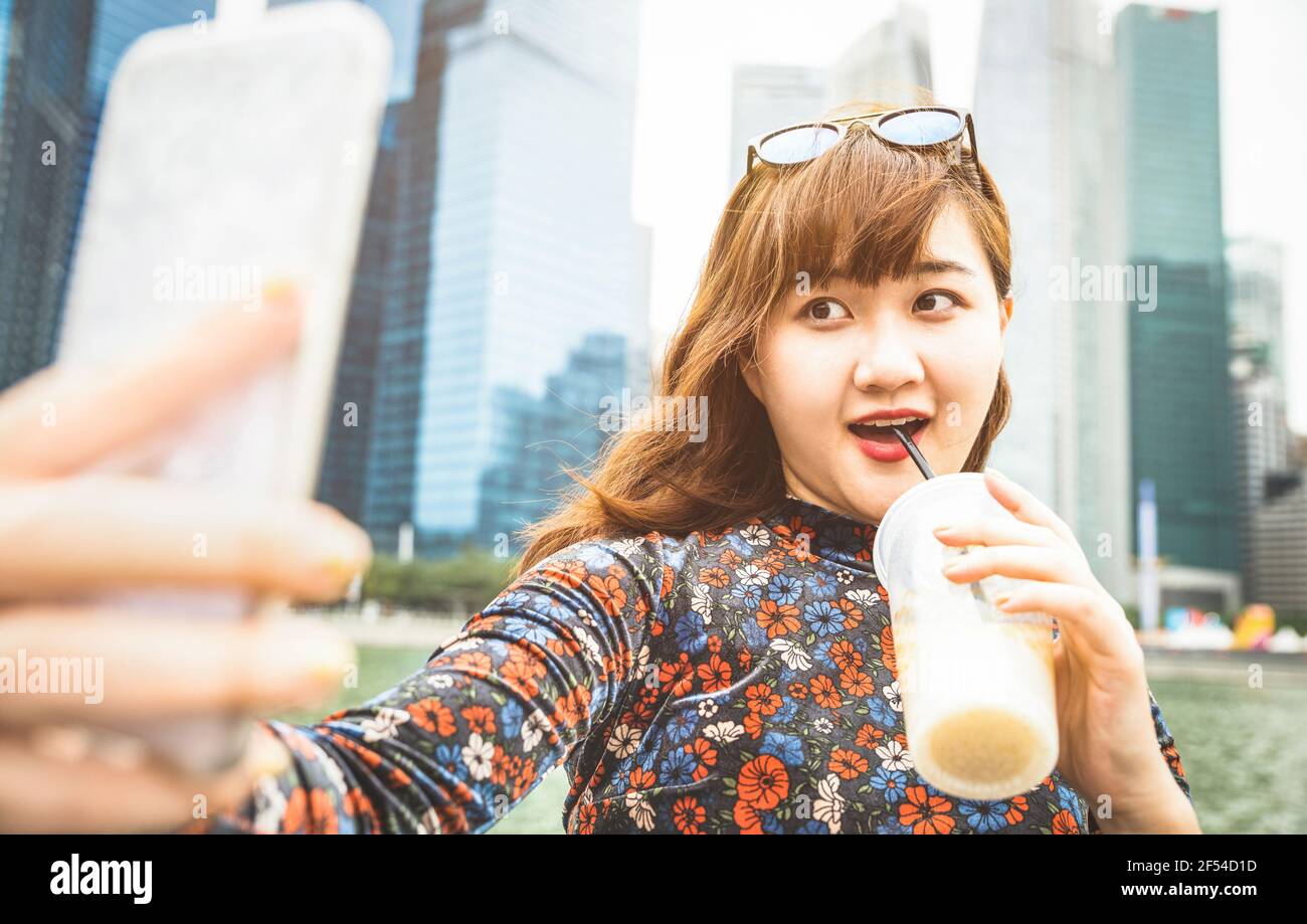 Bella donna asiatica wanderer che prende selfie a moderna area urbana Di Marina Bay sullo skyline di Singapore al tramonto - Avventura stile di vita di viaggio Foto Stock