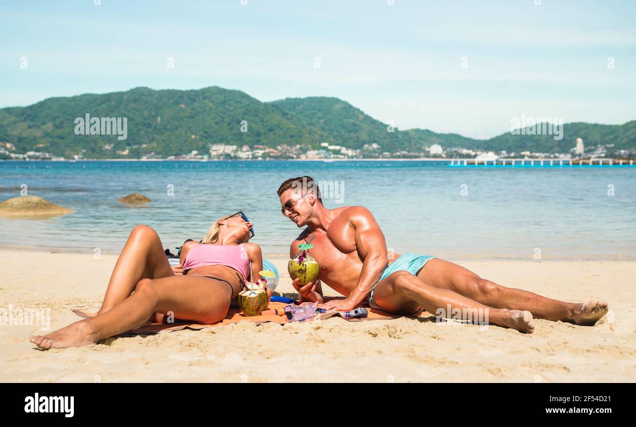 Giovane coppia vacanziere con vero divertimento sulla spiaggia tropicale di Phuket In Thailandia con bevanda di cocco - attivo amore giovanile e. concetto di viaggio in tutto il mondo Foto Stock
