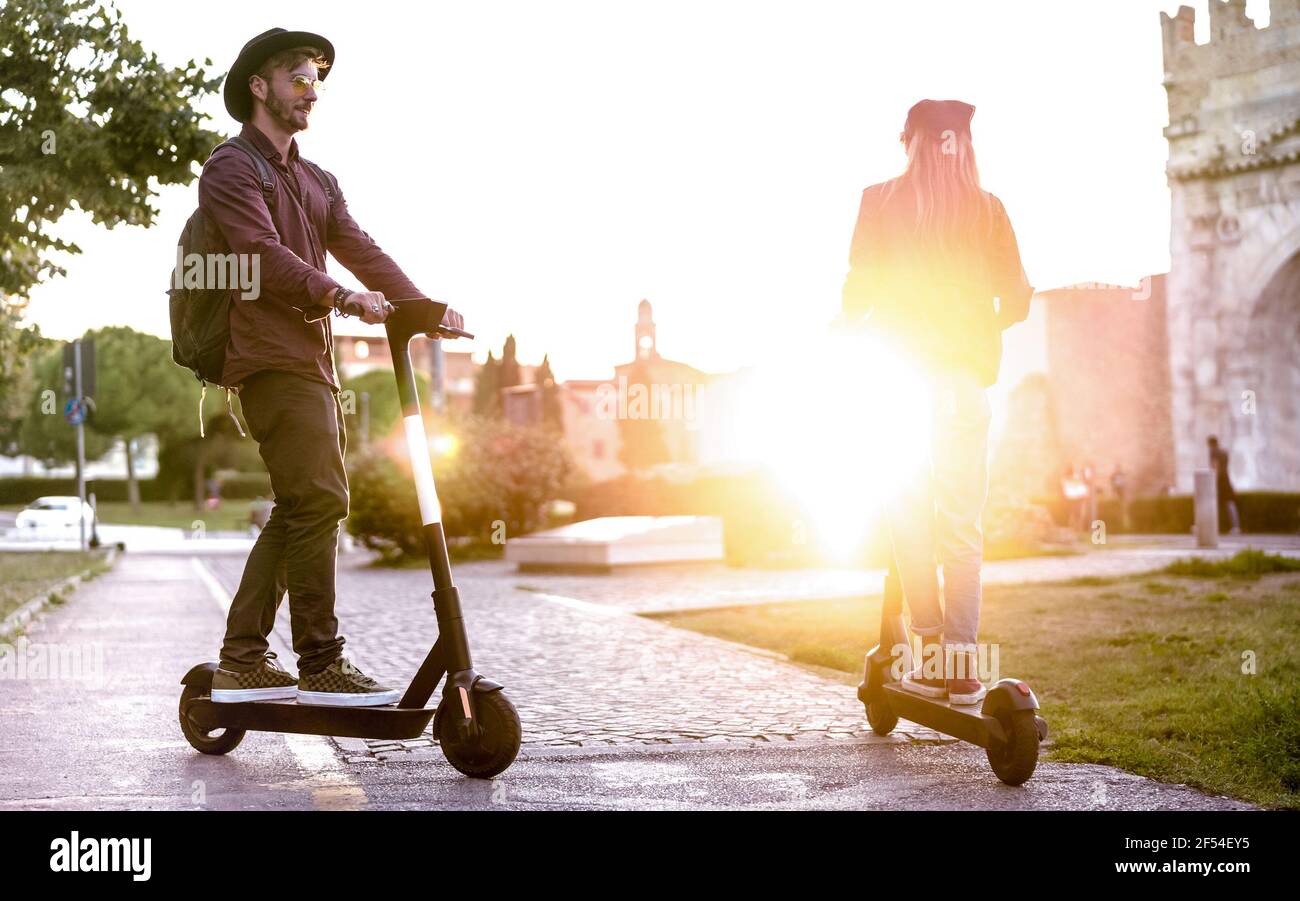 Coppia moderna che usa uno scooter elettrico nel parco cittadino - Milenial Studenti che cavalcano nuovi mezzi ecologici di trasporto - Green eco concetto di energia Foto Stock