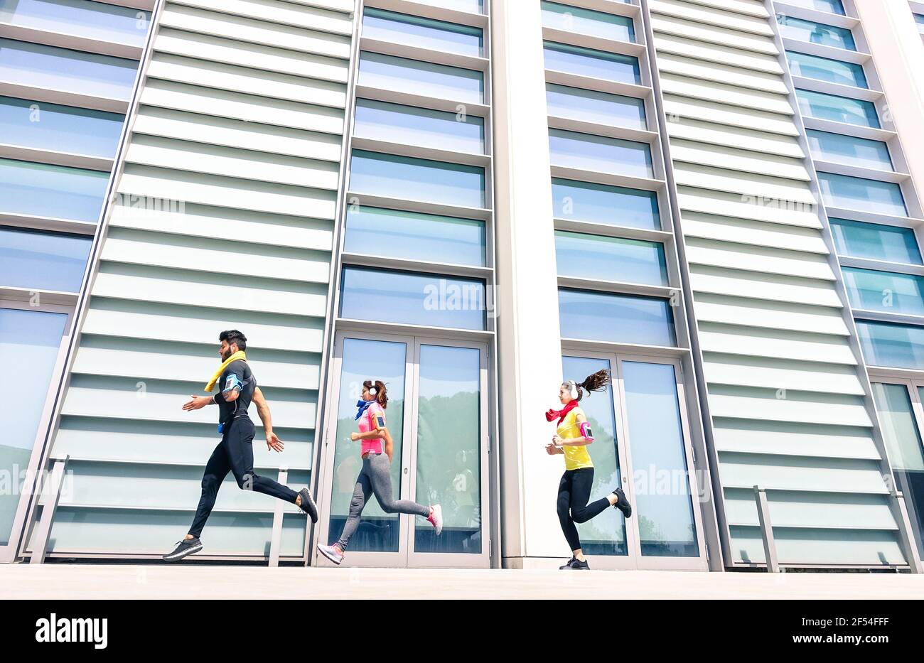 Gruppo di giovani che corrono in un'area urbana moderna - Fitness ragazze che corrono con allenatore maschile in città - concetto di sport con amici jogging Foto Stock