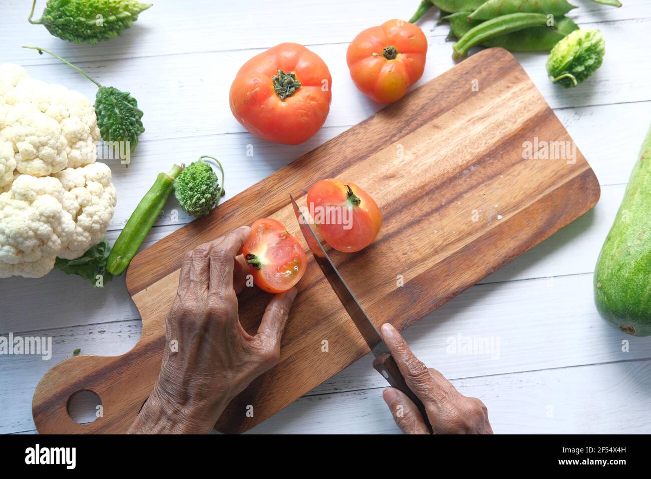 donne anziane che tagliano i pomodori su un tagliere dall'alto verso il basso Foto Stock