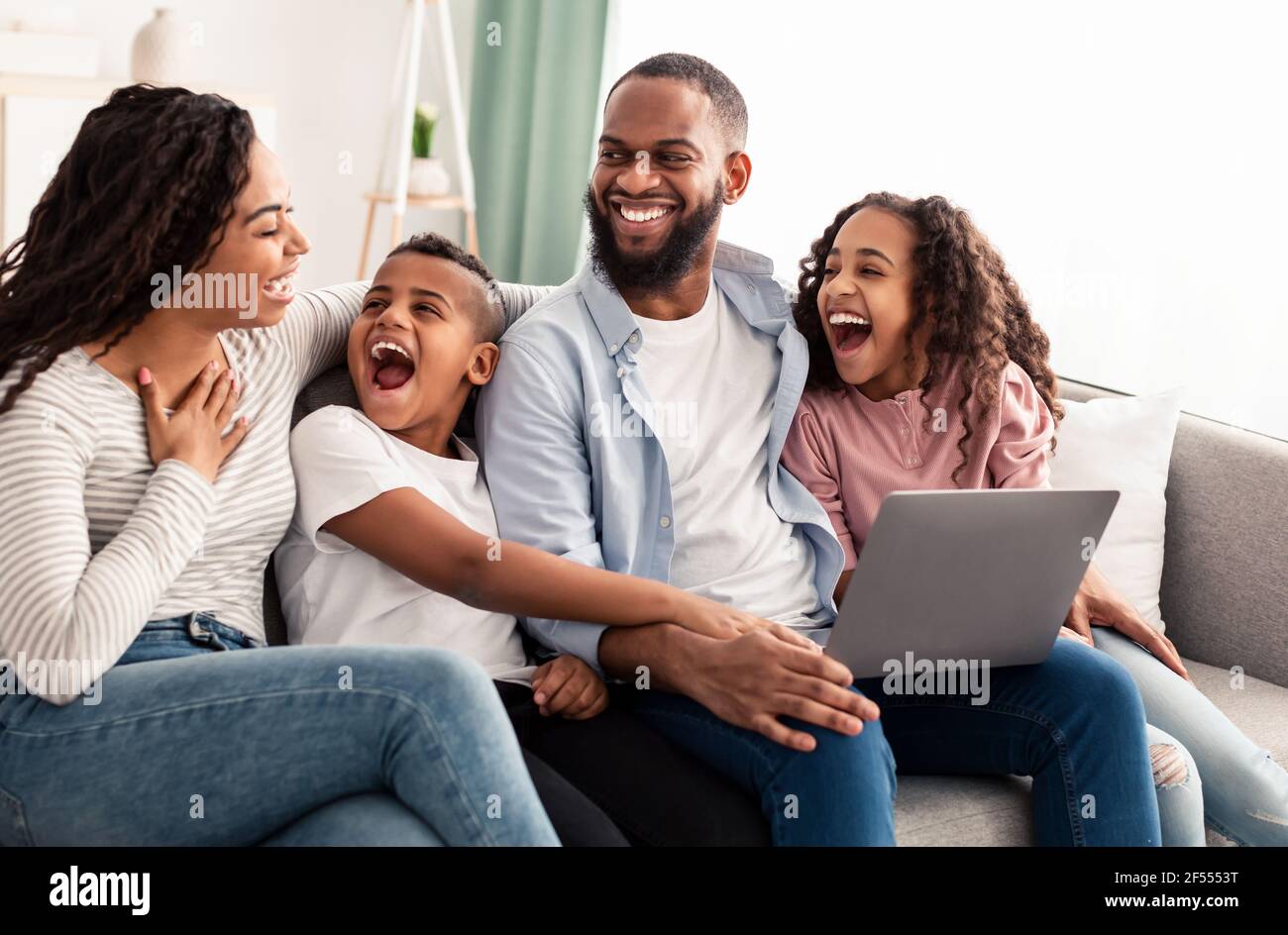 Ridendo famiglia afroamericana usando il laptop in salotto Foto Stock