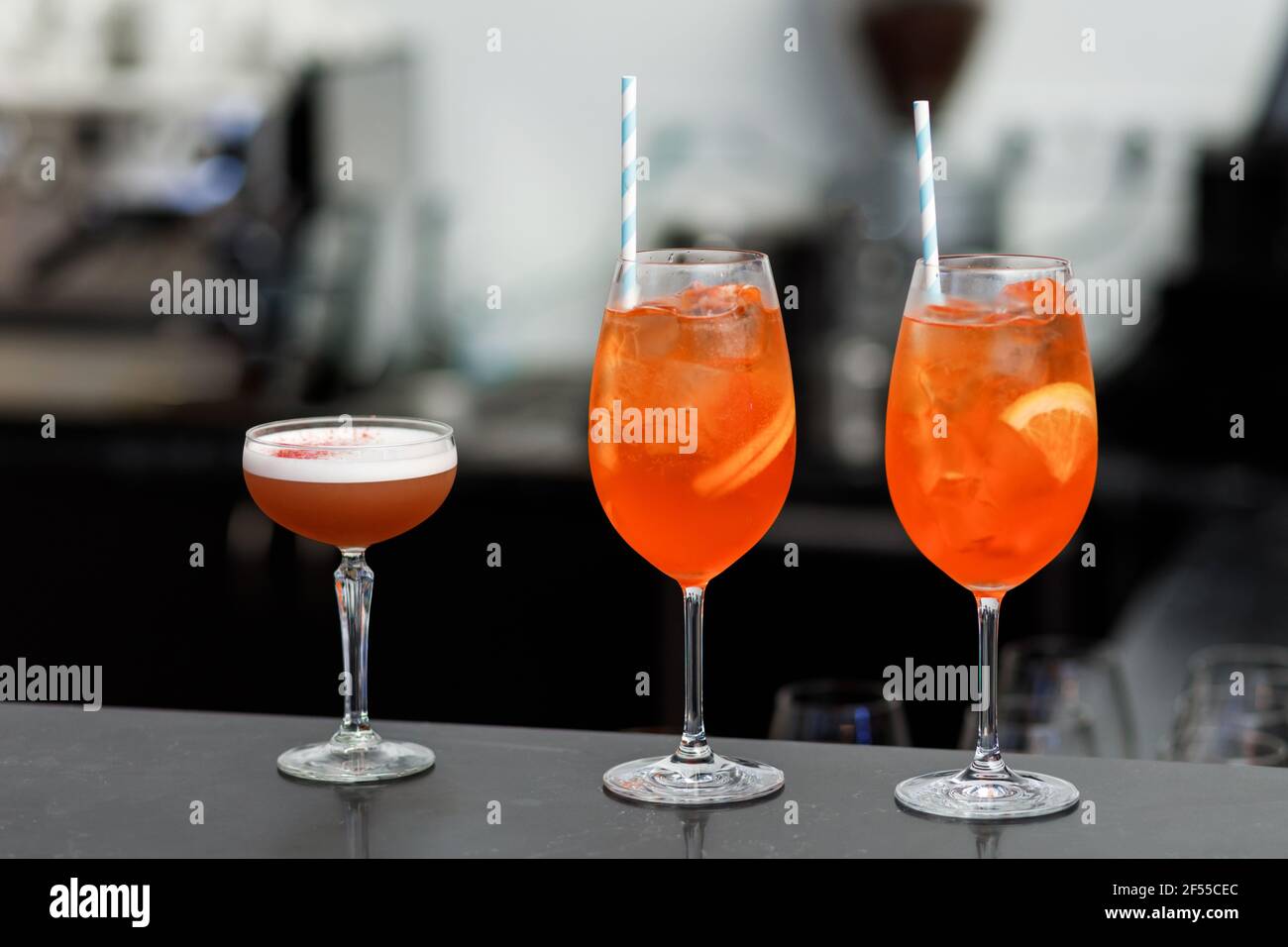 Cinque i cocktail colorati preparati da un barman con pezzi di arancia e cubetti di ghiaccio. Foto Stock