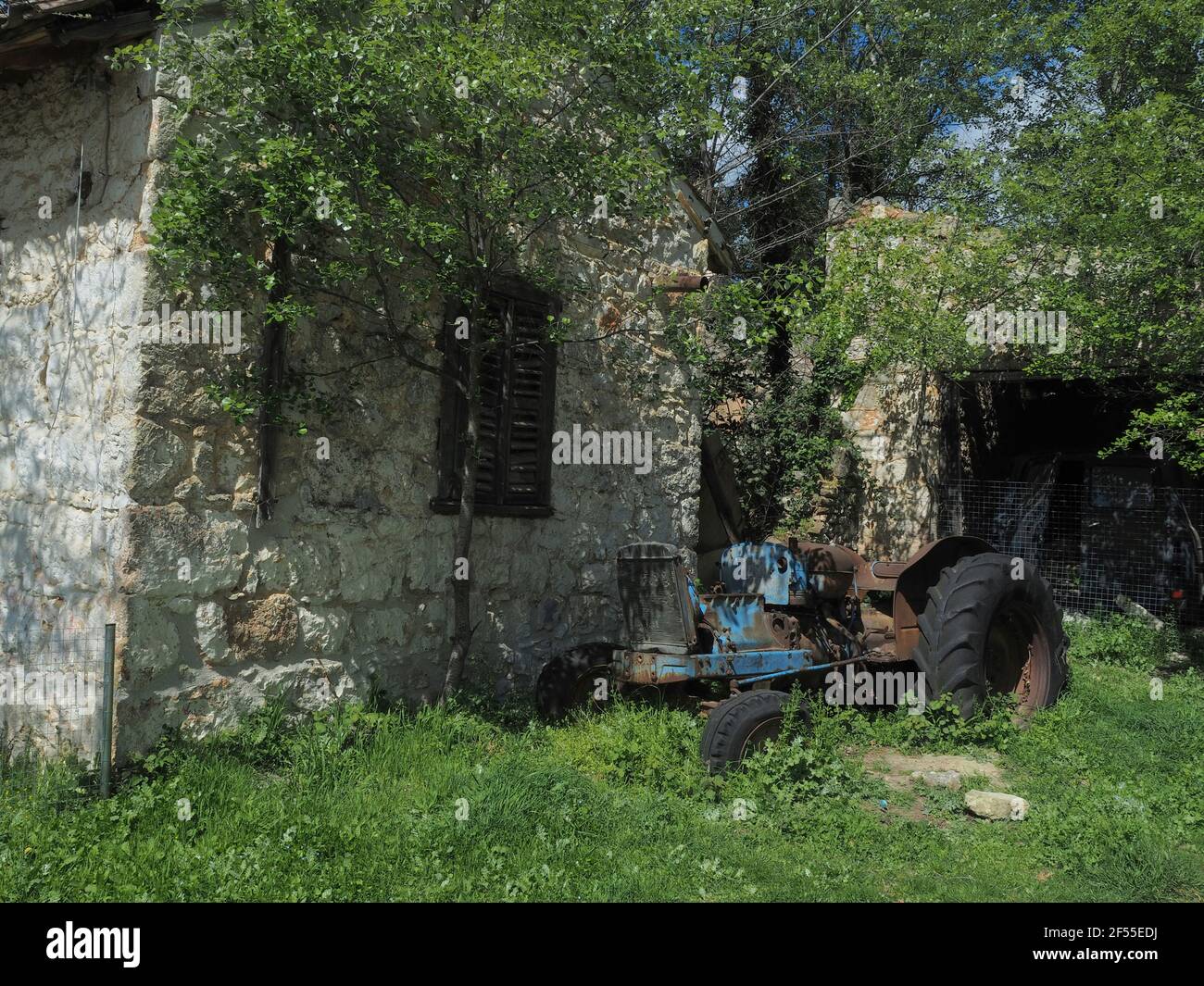 Vista del vecchio trattore arrugginito fuori dall'edificio abbandonato in pietra fattoria nel parco di Tatoi vicino Atene, Grecia. Foto Stock Vista del vecchio trattore arrugginito fuori dall'edificio abbandonato in pietra fattoria nel parco di Tatoi vicino Atene, Grecia. Foto Stock