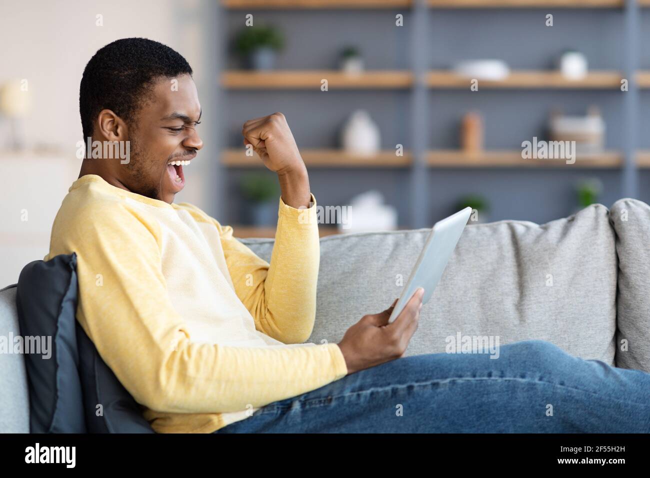 SDE vista di felice uomo nero con pad che celebra il successo Foto Stock