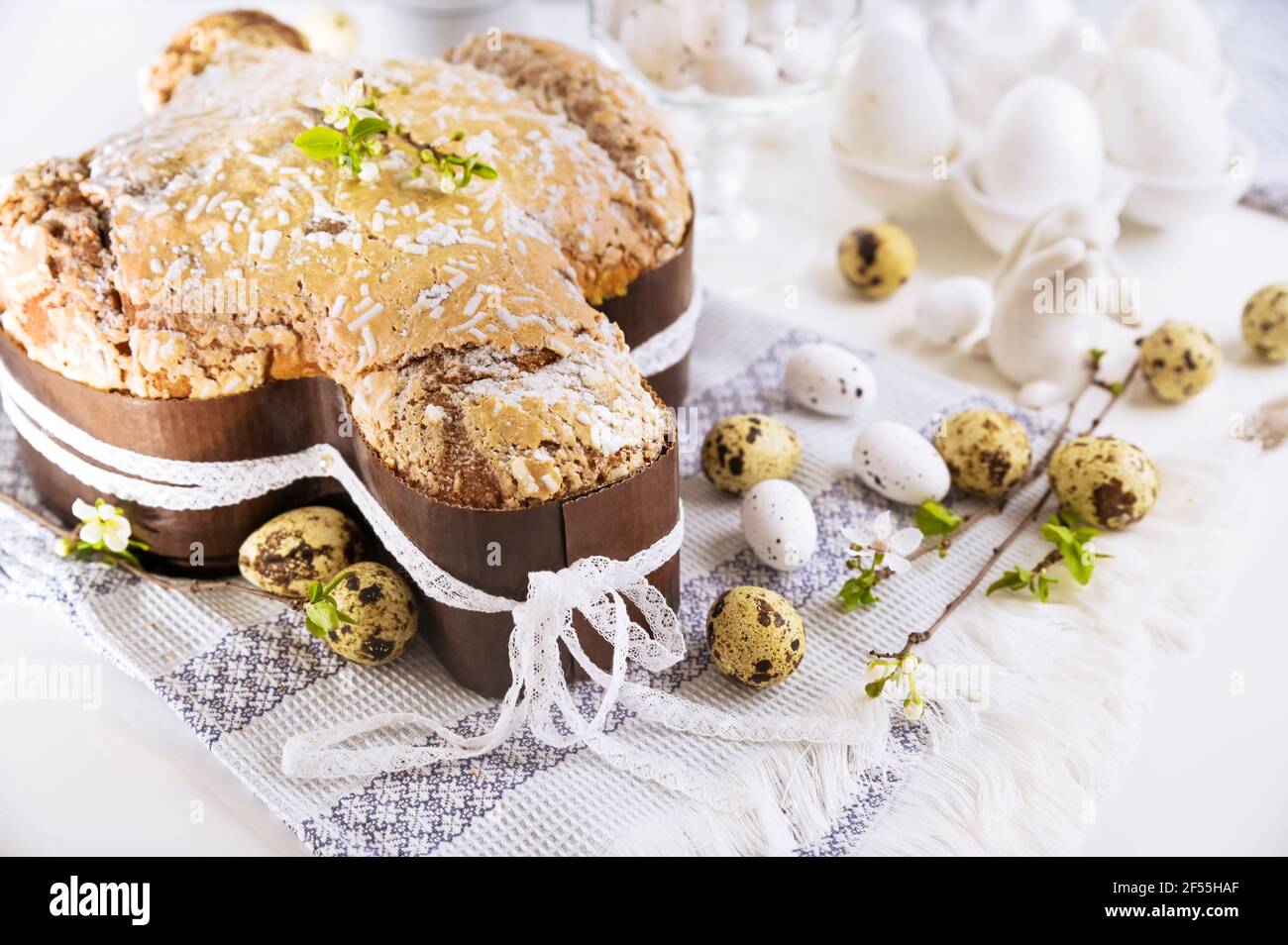 Dessert tradizionali italiani per Pasqua - colomba di Pasqua. Dolci natalizi con mandorle e glassa di zucchero su sfondo chiaro e rami fioriti, decorazioni pasquali e uova. Primo piano Foto Stock