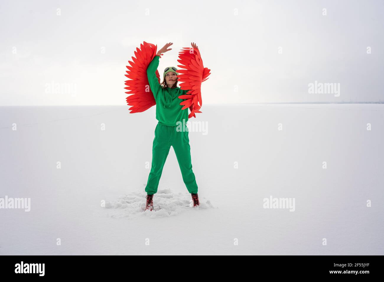 Donna in costume verde uccello guardando in su mentre si sta in piedi contro cielo Foto Stock