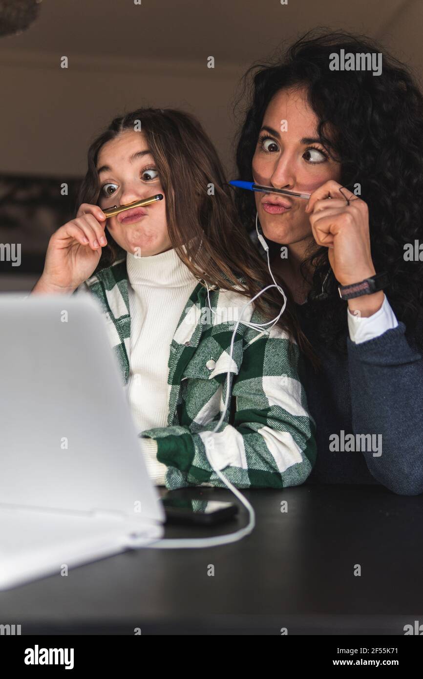 Madre e figlia giocosa che fanno i volti a casa Foto Stock