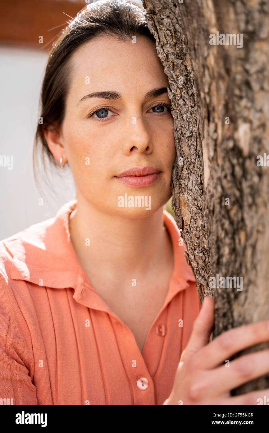 Bella donna che abbraccia tronco d'albero in giardino Foto Stock