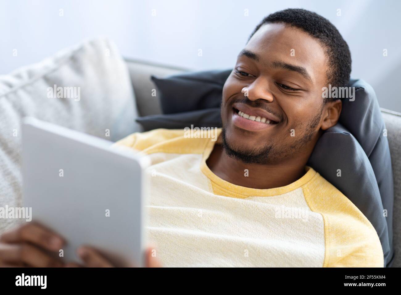 Primo piano di un ragazzo nero sorridente che utilizza un tablet digitale Foto Stock