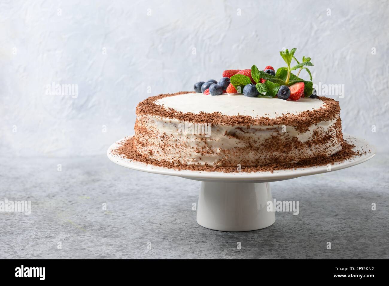Gustosa torta fatta in casa di mascarpone e biscotto decorato frutti di bosco, menta, fragole e mirtilli. Foto Stock