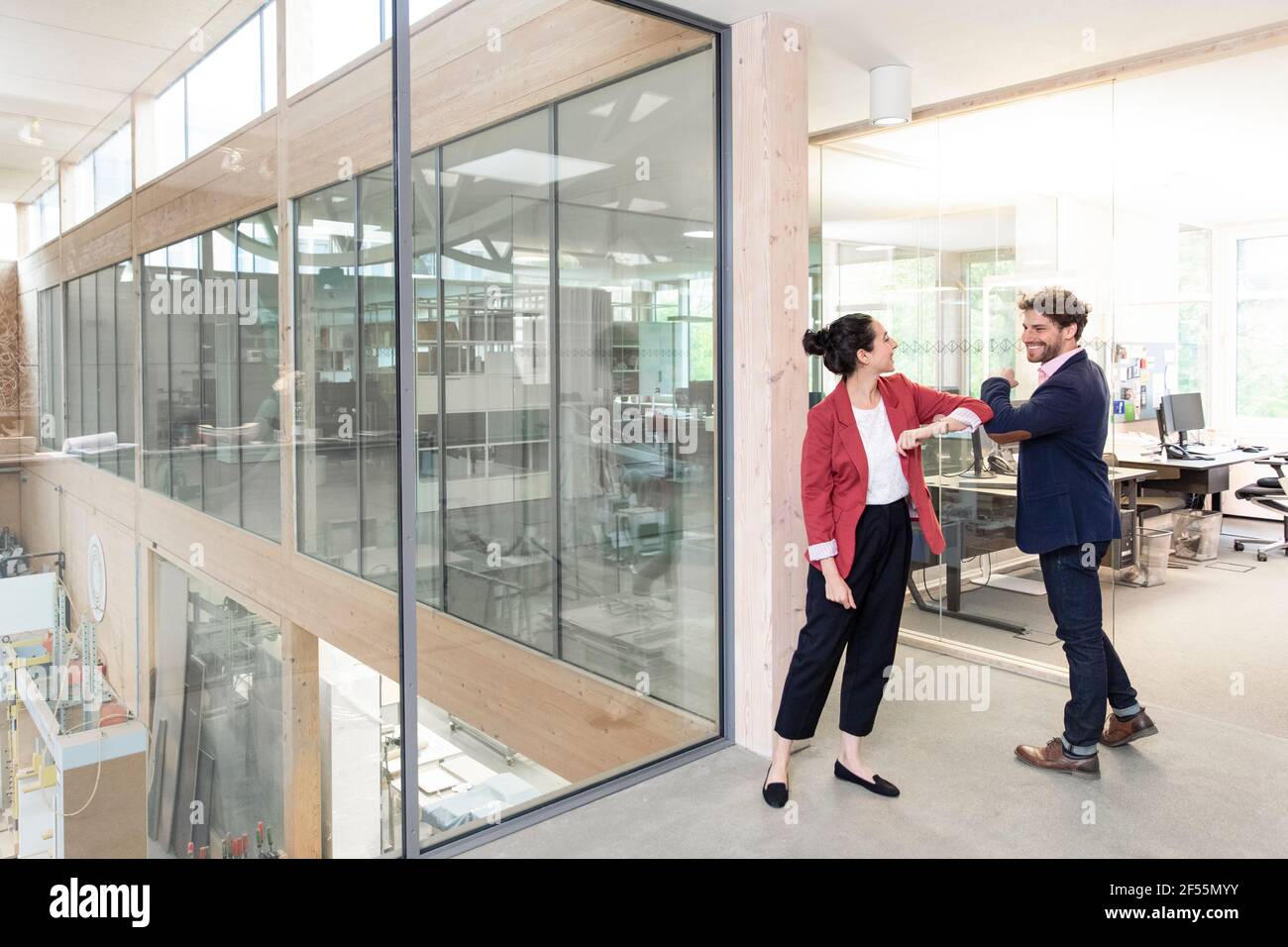 Sorridendo imprenditori maschili e femminili dando gomito a gomito in ufficio Foto Stock