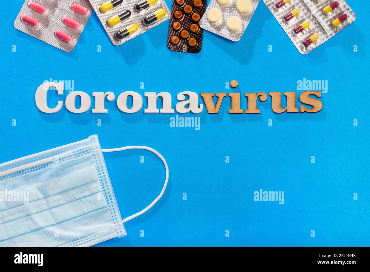 Testo della frase del coronavirus su sfondo blu con farmaci e maschere protettive. Foto Stock