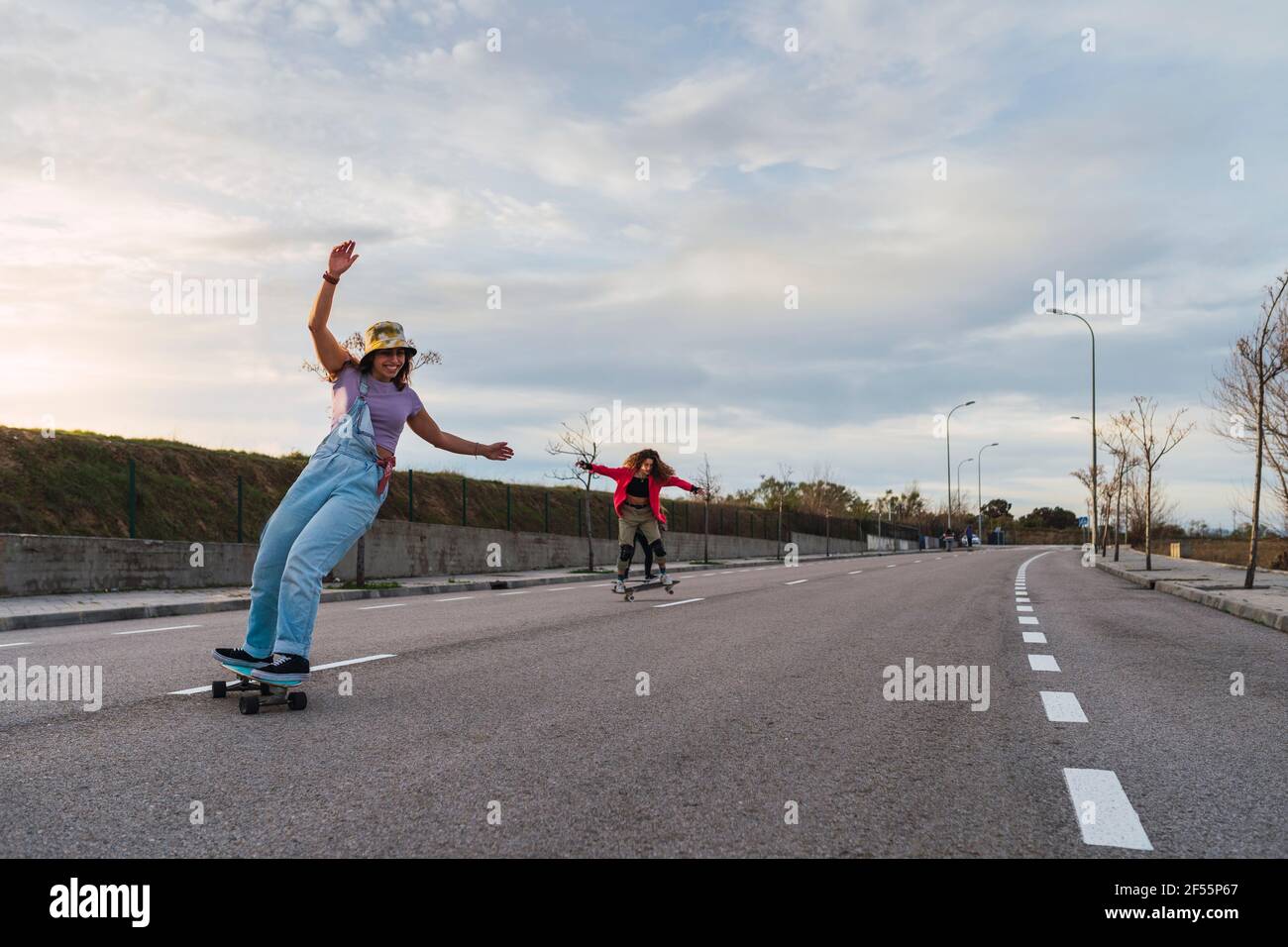 Le amiche si divertono mentre guidano i pattini sulla strada Foto Stock