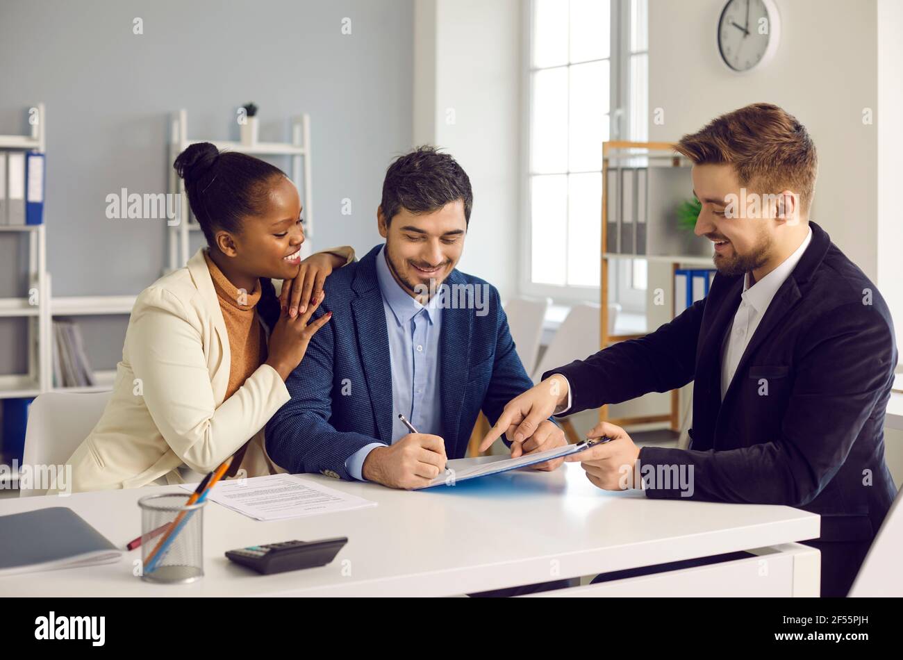 Felice coppia di etnia mista clienti firmare il contratto di prestito ipotecario documento Foto Stock
