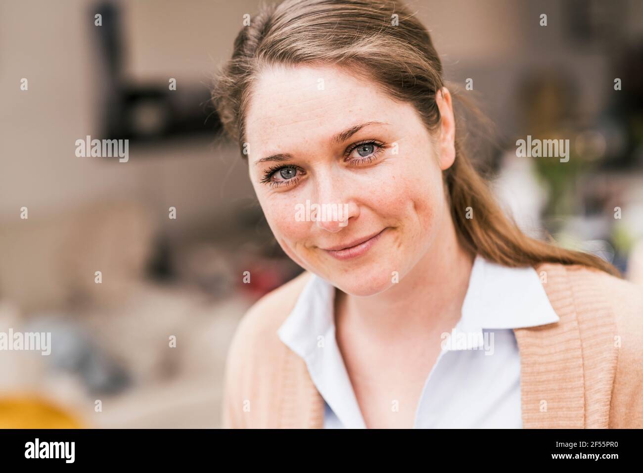 Donna sorridente professionista in maglione cardigan a casa Foto Stock