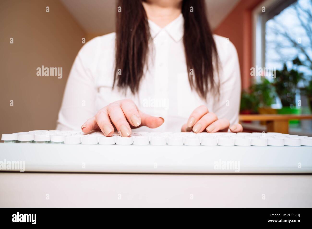 Primo piano donna che scrive su tastiera bianca. Lavorare dal concetto domestico. Foto Stock