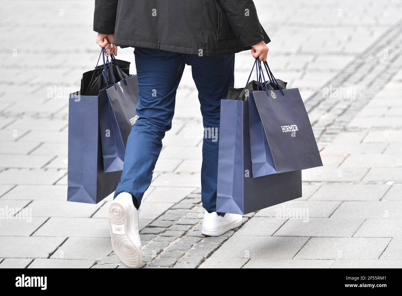 Monaco, Germania. 23 marzo 2021. Immagine tema shopping. La persona porta borse per la spesa, borse, borse per il trasporto, borse per il trasporto di carta, borse per il trasporto di carta con acquisti presso il negozio di abbigliamento Hirmer di Monaco. Borse per la spesa. | utilizzo in tutto il mondo credito: dpa/Alamy Live News Foto Stock