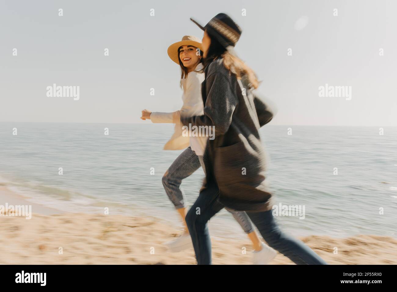 Felici fratelli che corrono in spiaggia il giorno di sole Foto Stock