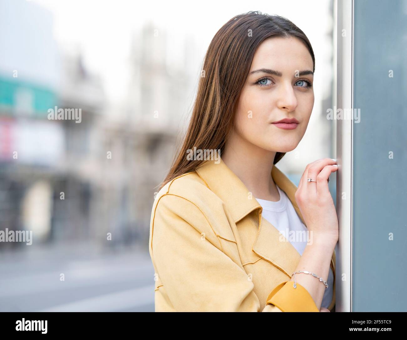 Bella donna con gli occhi blu appoggiati sul muro Foto Stock