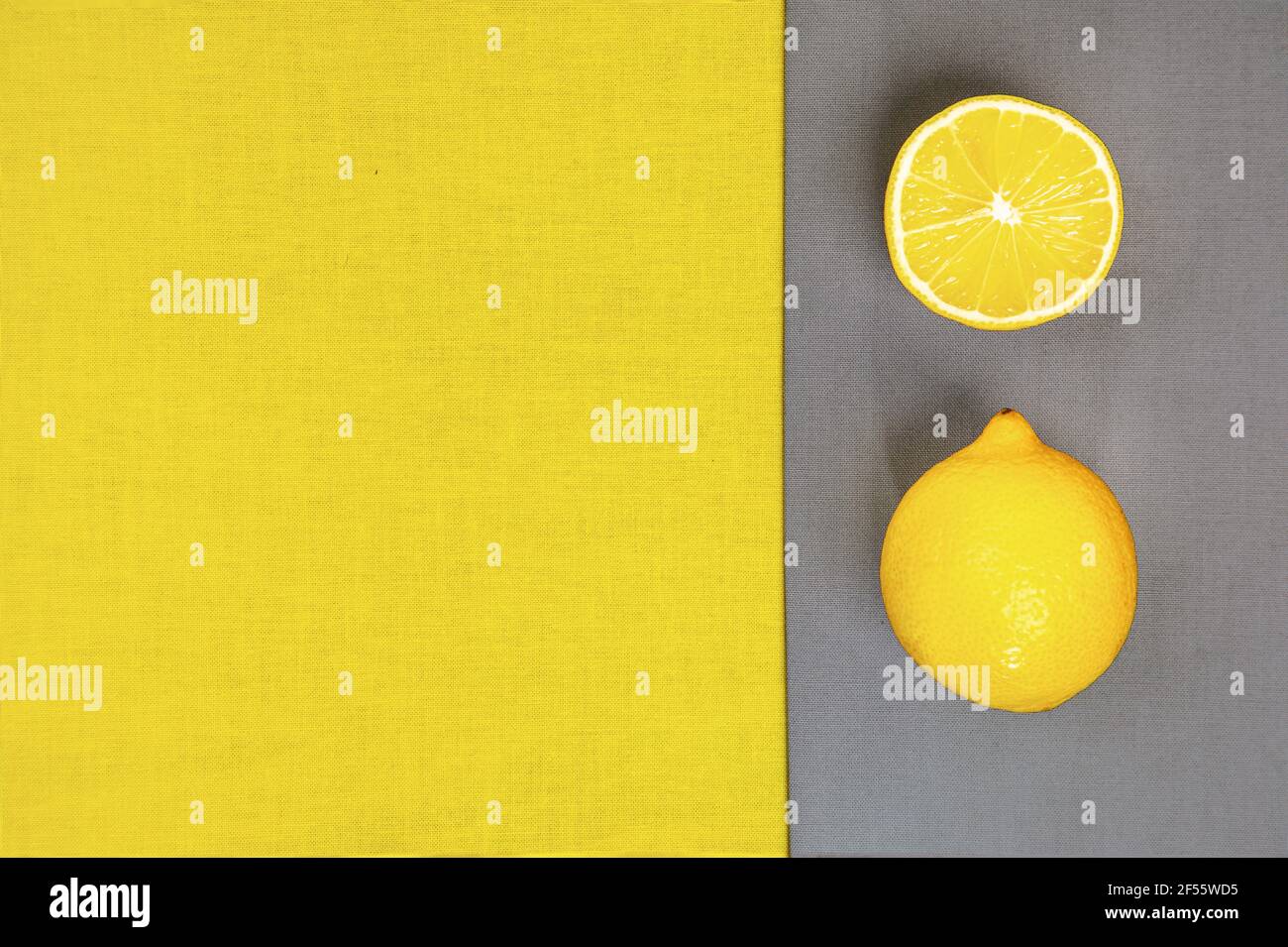 Colore trendy dell'anno 2021. Giallo luminoso e grigio estremo. Frutta al limone su fondo grigio, piatto. Foto Stock