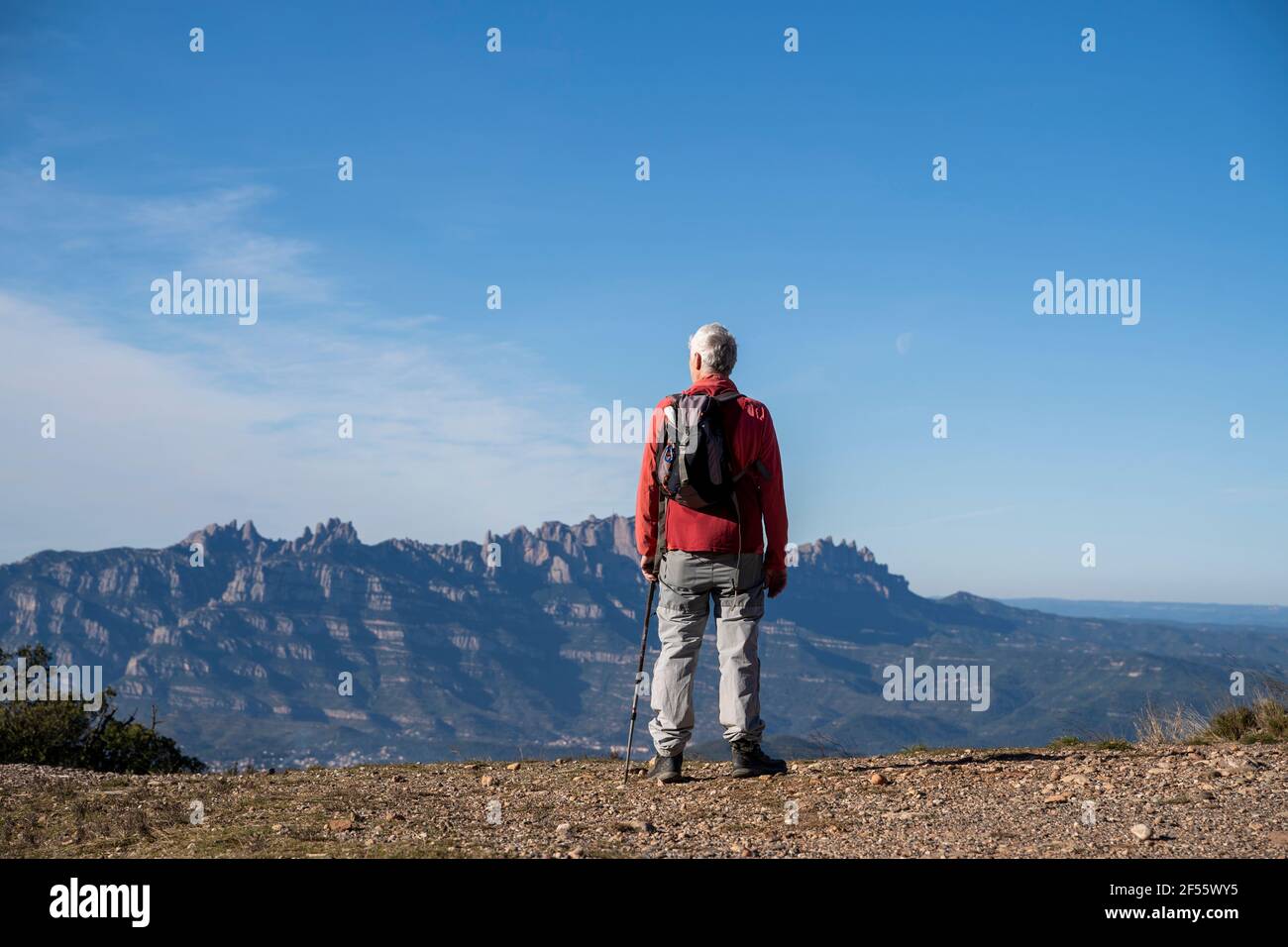 Escursionista senior con zaino che ammira la vista di Montserrat mentre si trova sulla montagna a Sant Llorenc del Munt i l'Obac, Catalogna, Spagna Foto Stock
