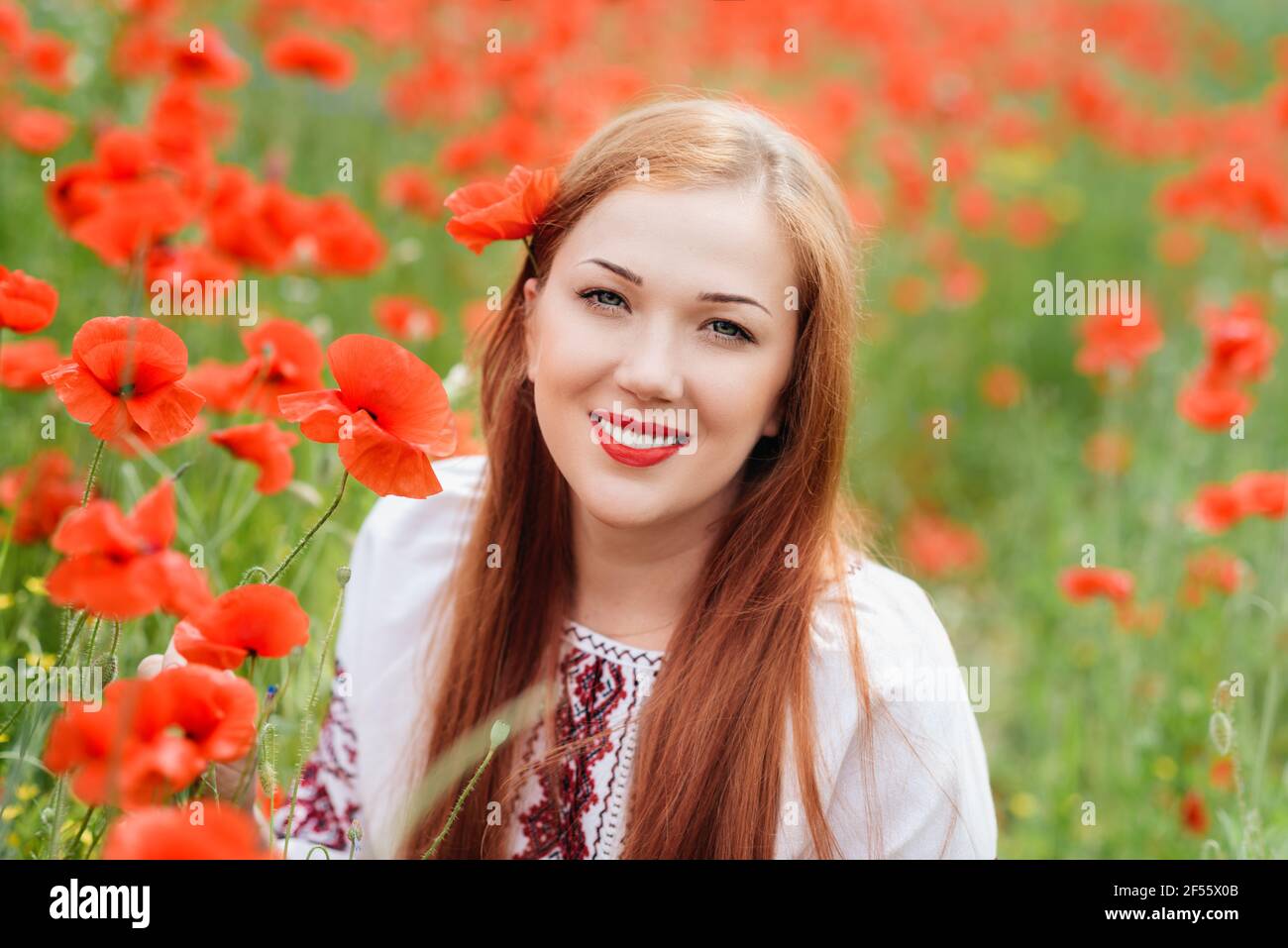Ucraino bella Donna in ricamo tradizionale in campo papaveri ritratto esterno. Raccolta papaveri e fiore di mais in campo estivo. Pop in fiore Foto Stock
