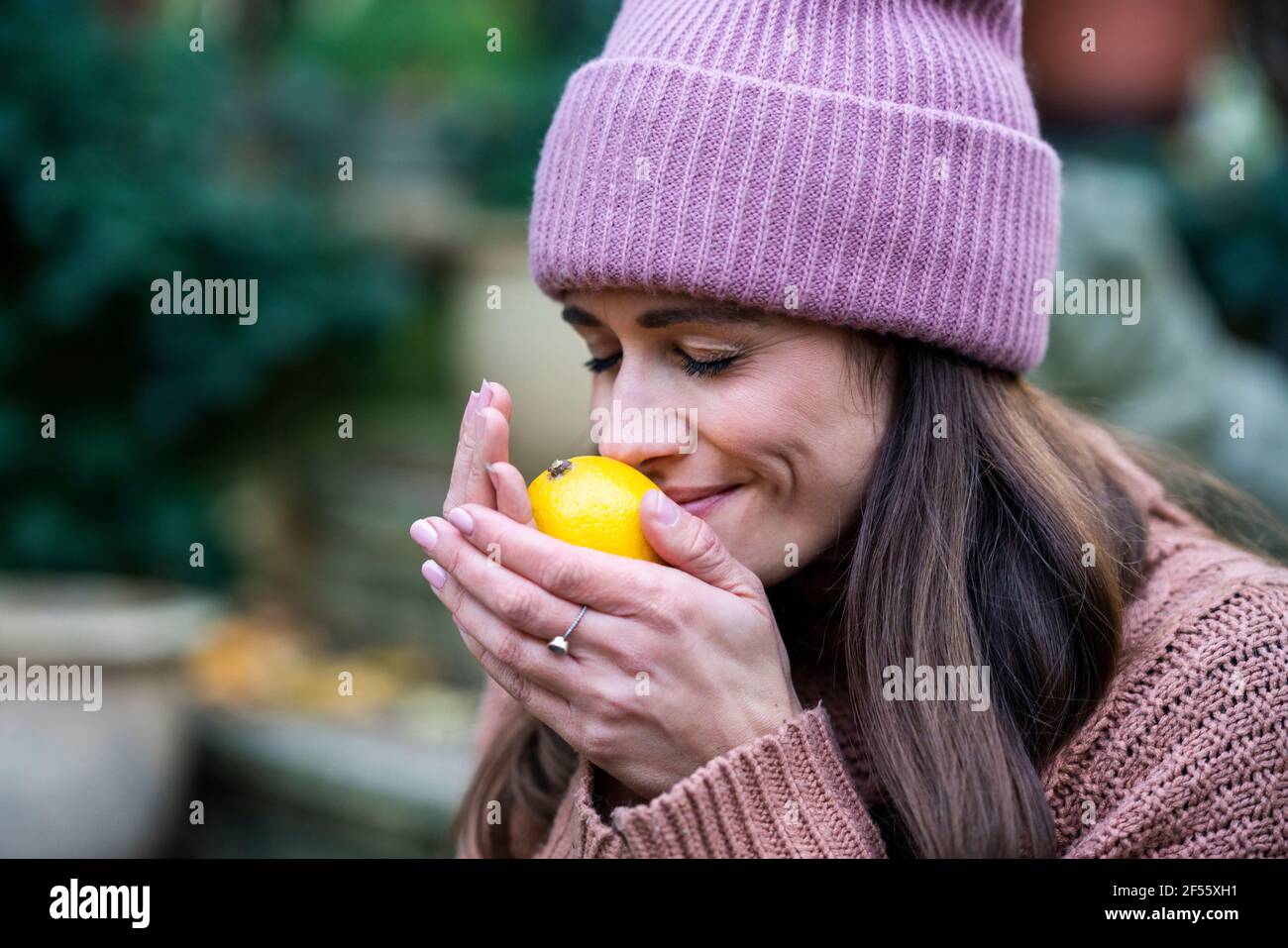 Ritratto di bella donna che indossa cappello rosa a maglia odore fresco limone con occhi chiusi Foto Stock