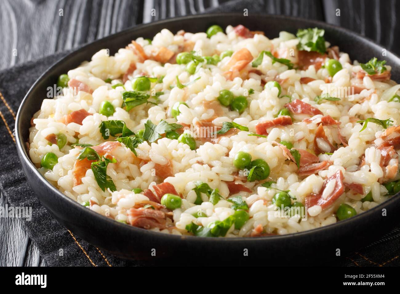 Risotto italiano Risi e Bisi a base di riso con piselli e prosciutto primo  piano in un piatto sul tavolo. Orizzontale Foto stock - Alamy