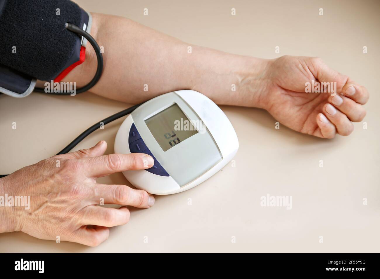 La pressione sanguigna controlla il tonometro man. Le mani e il dispositivo si trovano su un tavolo luminoso. Foto Stock