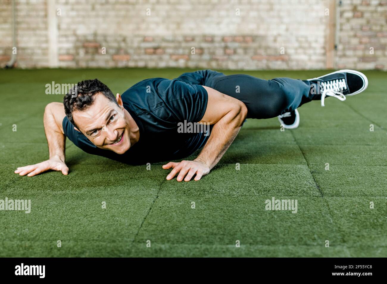 L'uomo sorridente è caduto mentre fa i spinta in su in salute club Foto Stock