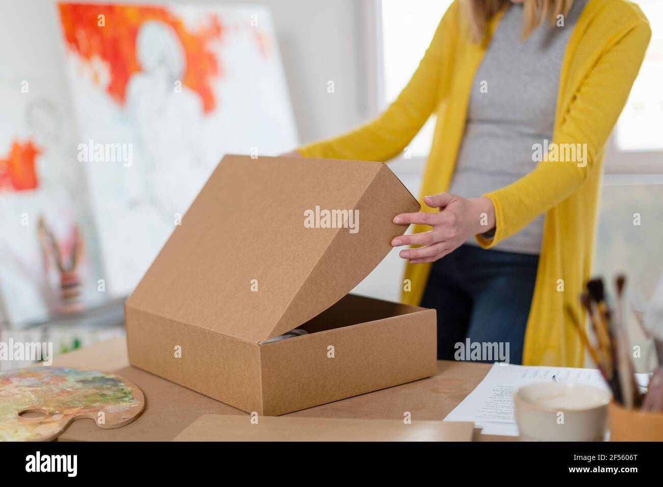 Donna disimballaggio scatola di cartone in casa studio Foto Stock