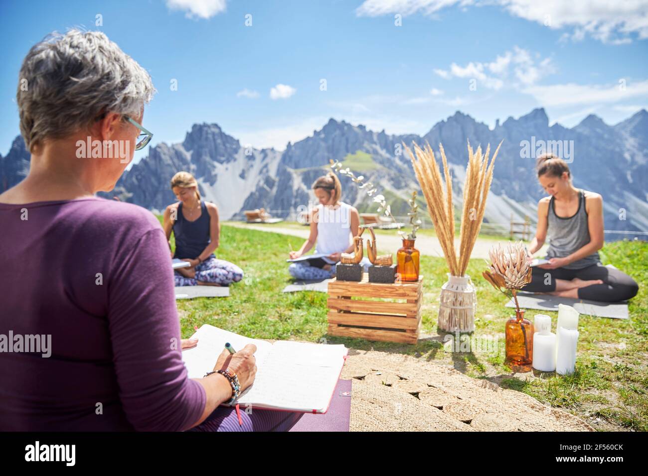 Amici femminili che scrivono nel libro il giorno di sole contro il cielo e la montagna Foto Stock