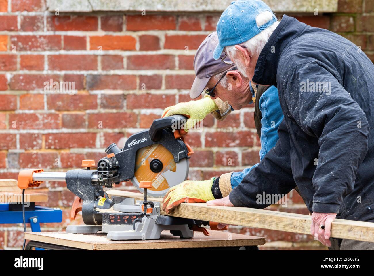Lavoratori anziani del legno e falegnami, due uomini più anziani che tagliano legno con una sega circolare, Alresford, Hampshire, Regno Unito Foto Stock