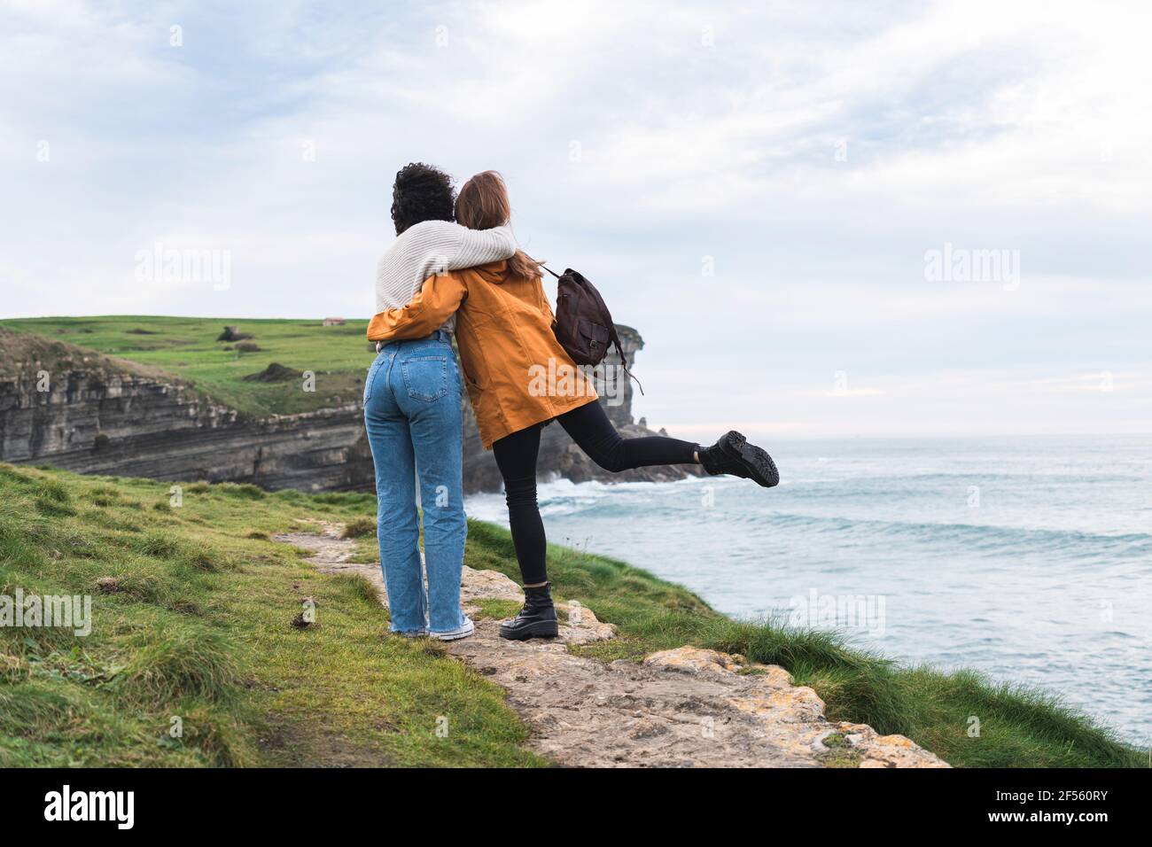 Giovani amici femminili in piedi con le braccia intorno a. Acantilado El Bolao Foto Stock