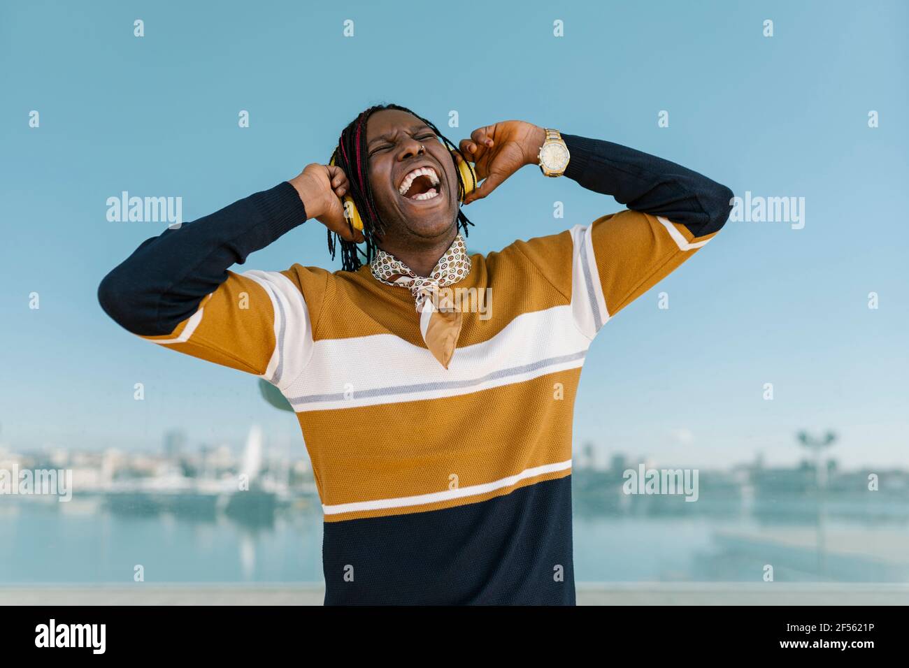 Un uomo africano allegro che ascolta la musica attraverso le cuffie Foto Stock
